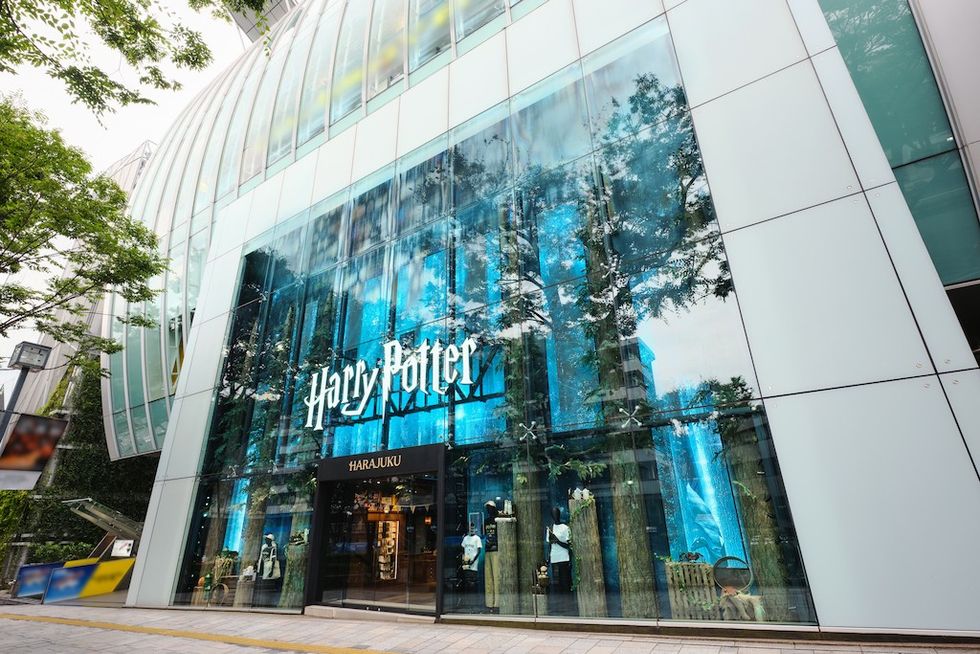 Large glass storefront with "Harry Potter" and "Harajuku" signs, trees reflected on glass.