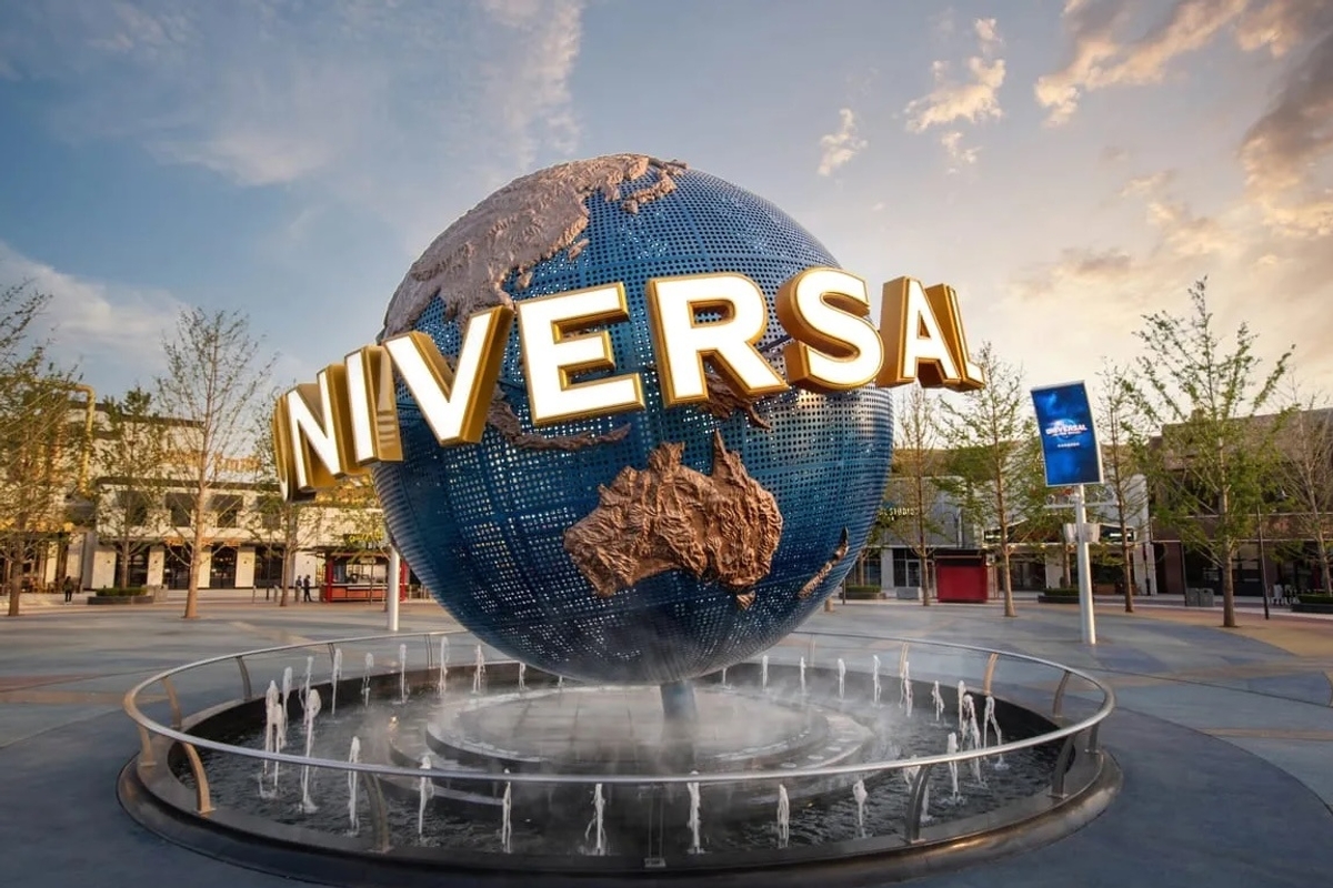 Large globe fountain with "UNIVERSAL" letters in a plaza at sunset.