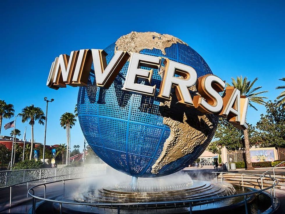 Large globe fountain with "Universal" text, surrounded by palm trees under a clear blue sky.