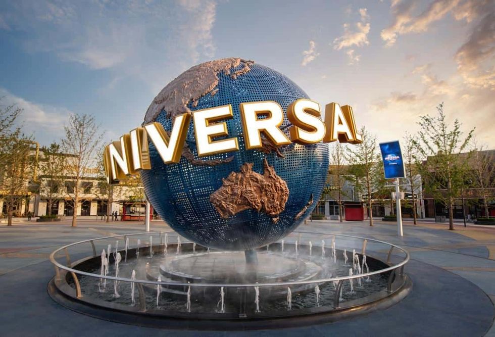 Large globe with "UNIVERSAL" sign and a fountain at an amusement park entrance.