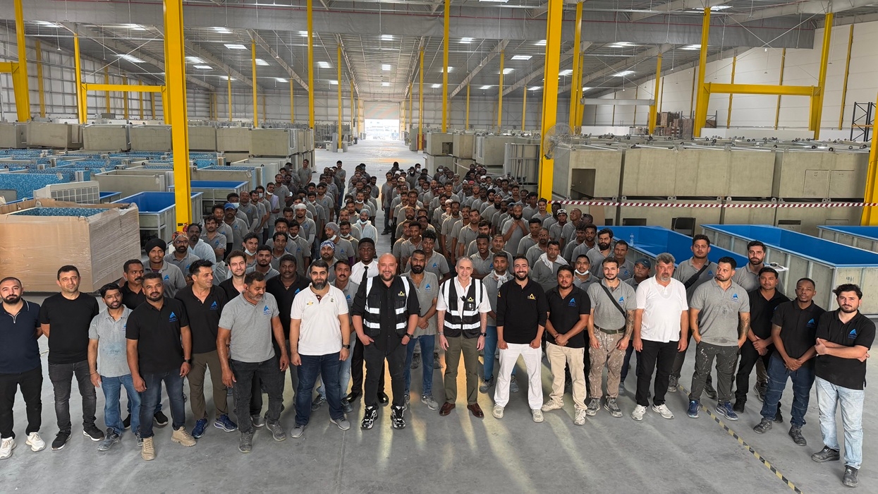 Large group of workers posing inside a spacious industrial warehouse at MAT Filtration Technologies' new UAE facility.