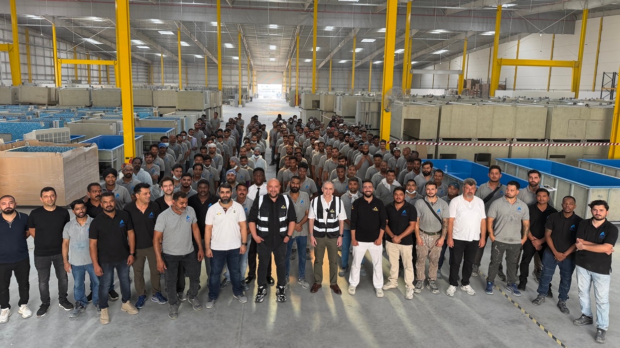 Large group of workers posing inside a spacious industrial warehouse at MAT Filtration Technologies new UAE facility.