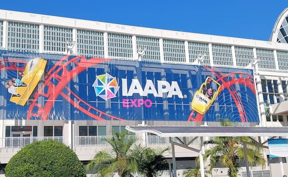 Large IAAPA Expo banner with roller coaster graphics on building exterior.