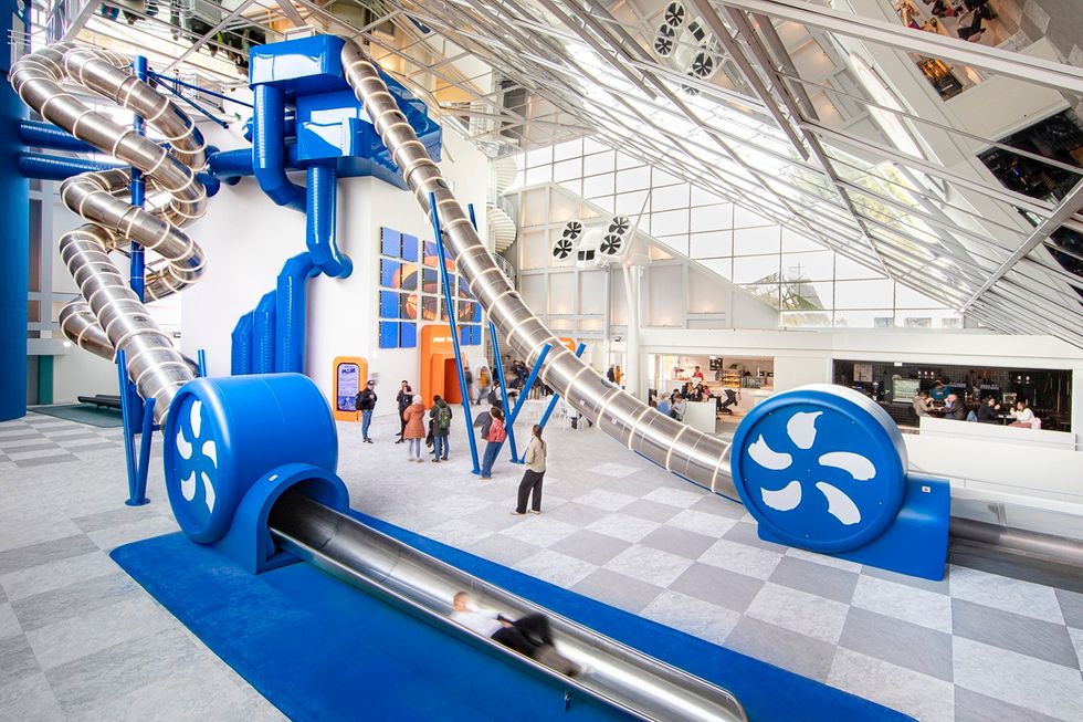 Large indoor slide in a modern building interior with people observing at Pulse! The Electric Odyssey