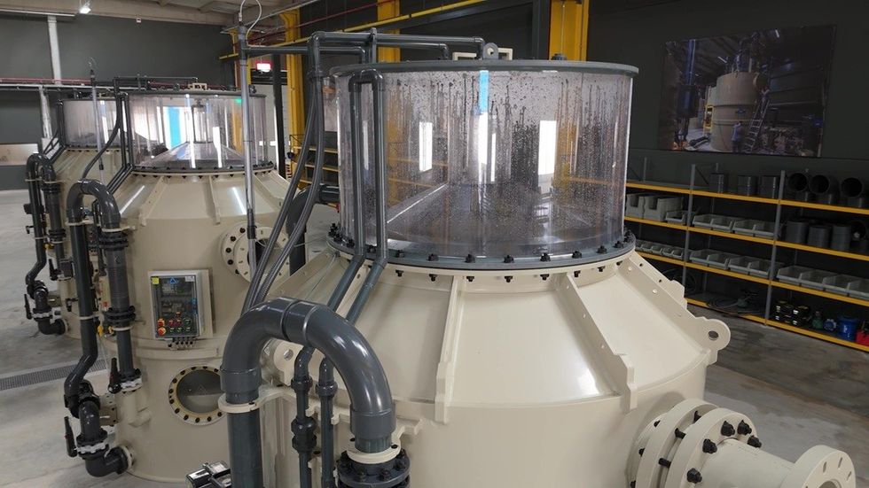 Large industrial machine with pipes and control panel in a workshop setting.