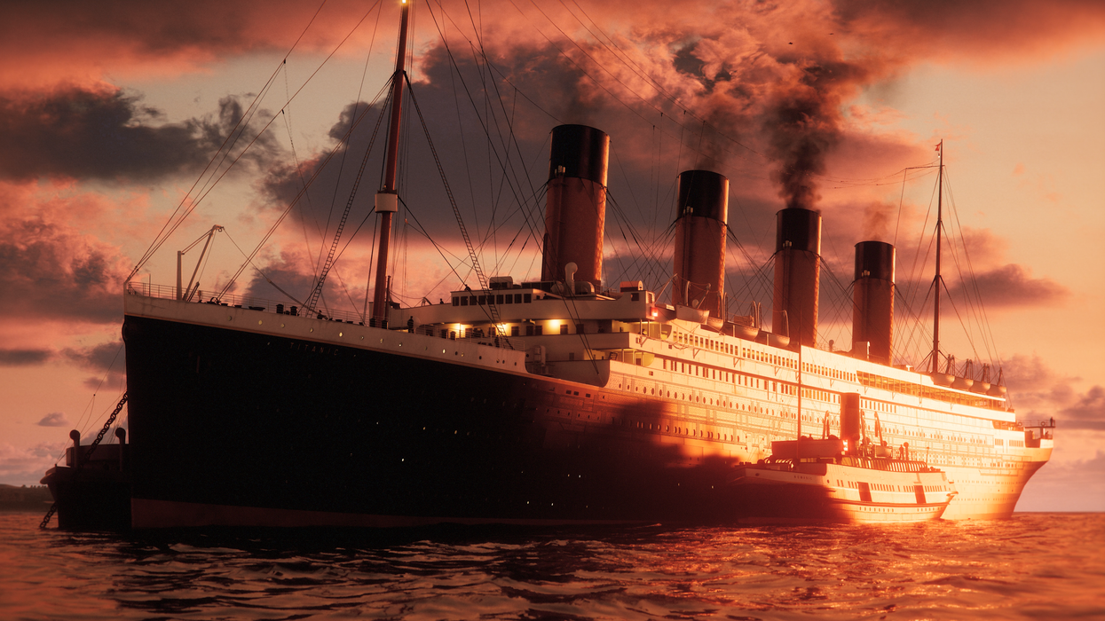 Large ocean liner at sunset with smoke billowing from smokestacks.