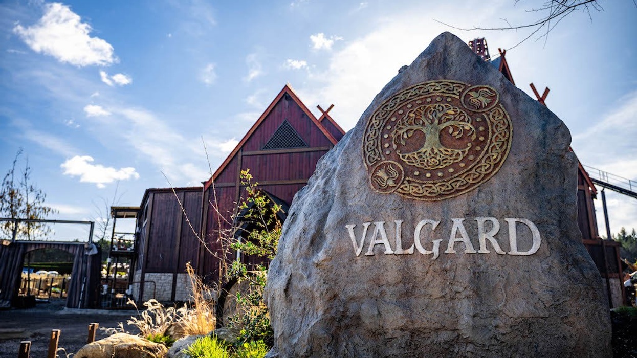 Large rock with "VALGARD" inscription, Nordic design, wooden building in background.