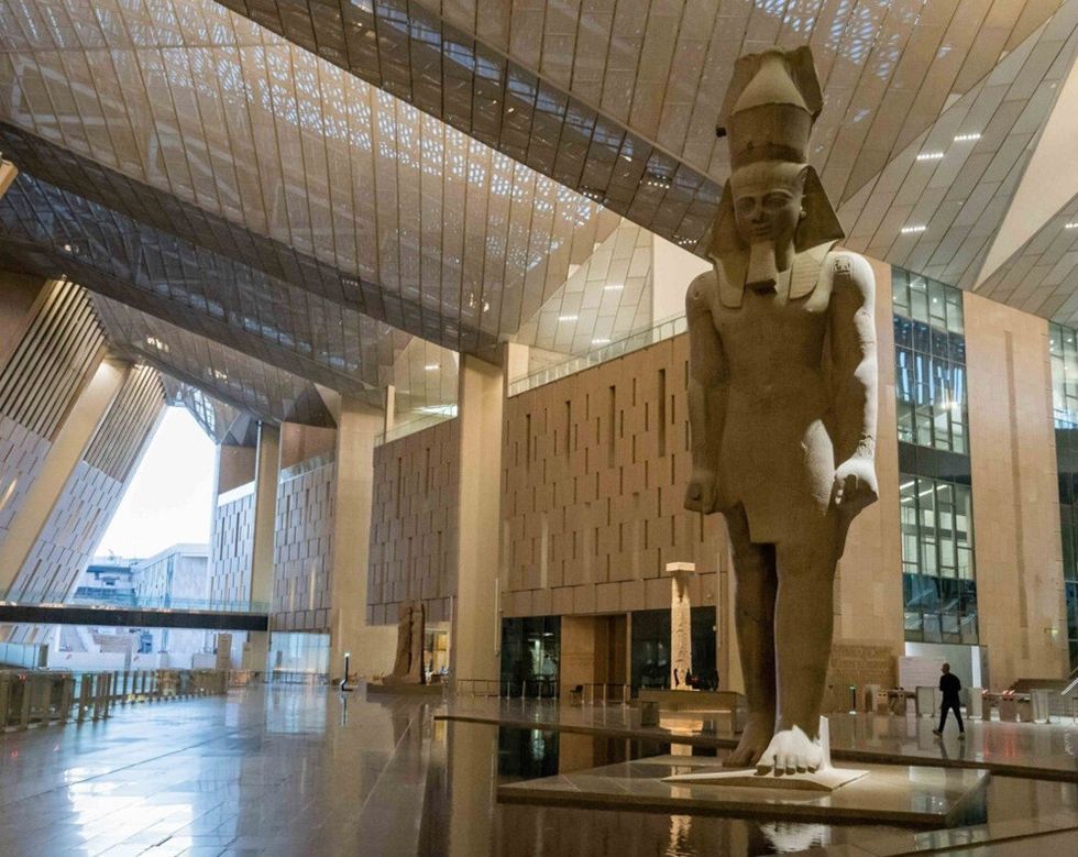 Large statue of an ancient figure inside a modern, spacious museum atrium.