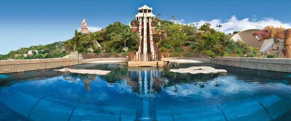 Large water slide in a tropical-themed water park with clear skies.