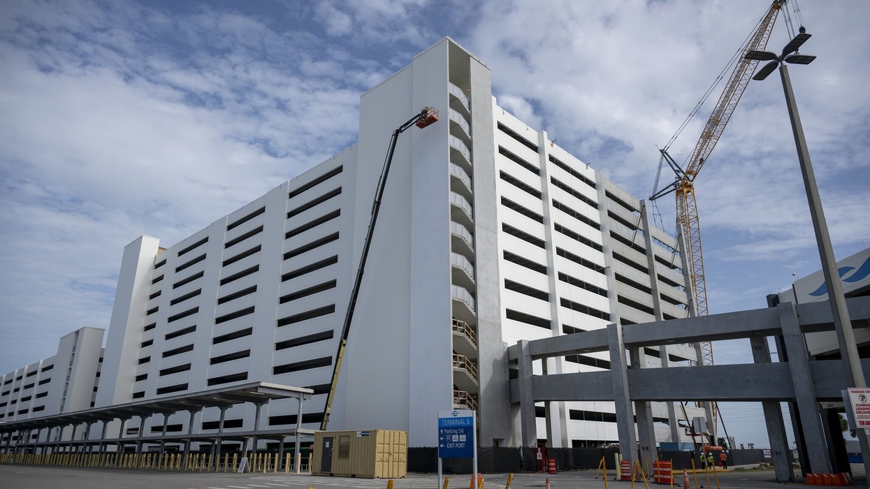 Large white multi-story parking garage under construction with crane and worker lift at Port Canaveral
