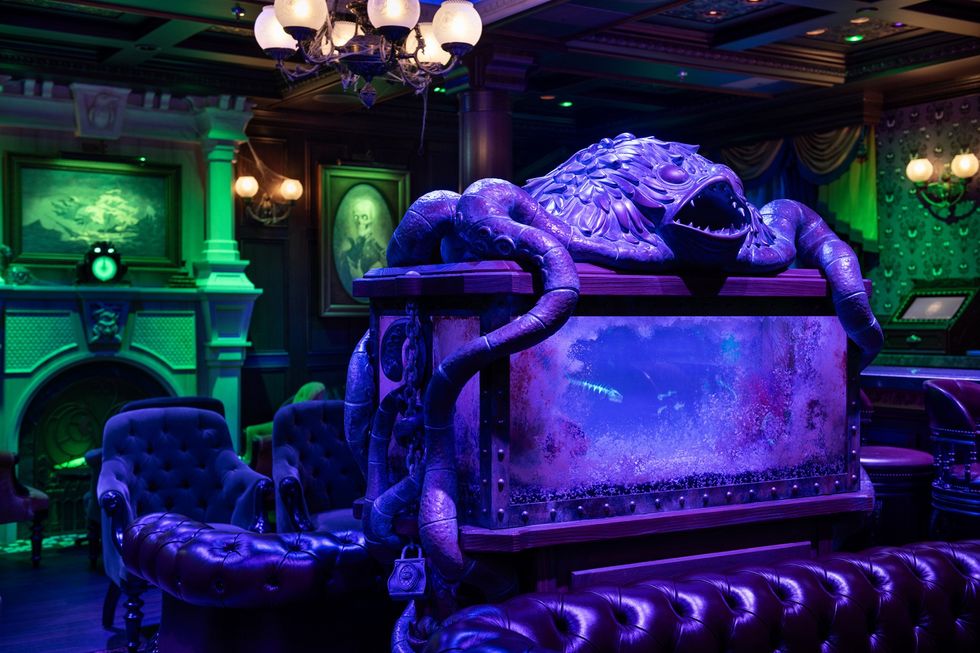 Lavishly decorated room with aquatic-themed sculpture and vintage furniture, under moody lighting.