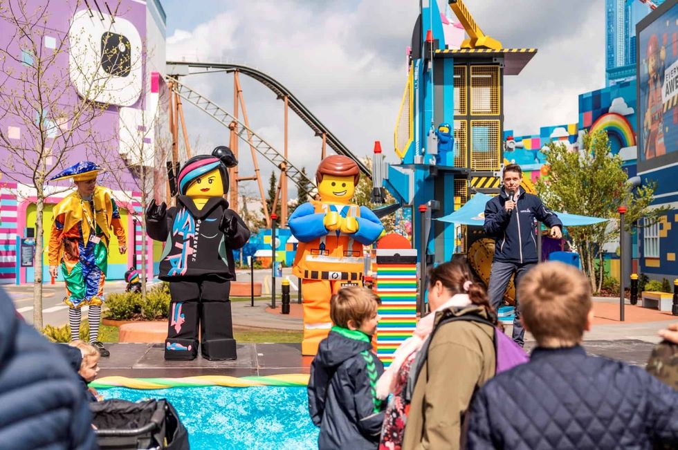 Lego character mascots entertaining children at a theme park event.