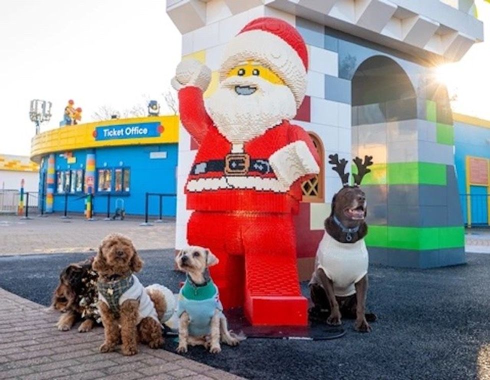 Lego Santa with four dressed-up dogs outside a colorful ticket office.
