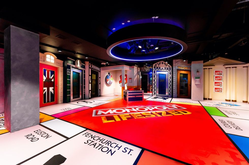 Life-sized Monopoly board with vibrant colors and themed rooms.