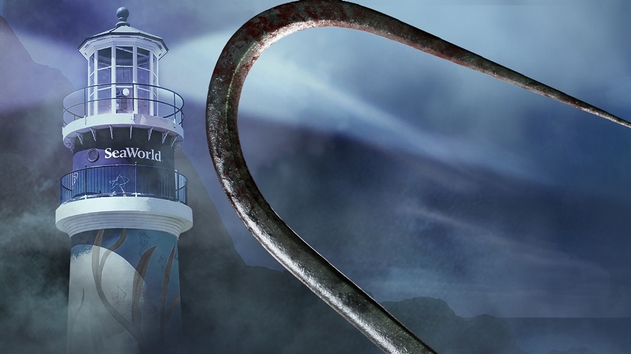 Lighthouse with "SeaWorld" sign and giant hook under a cloudy, misty sky.