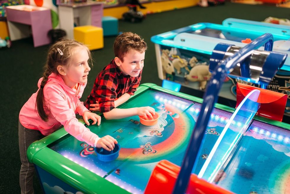 Little kids plays air hockey in entertainment center.