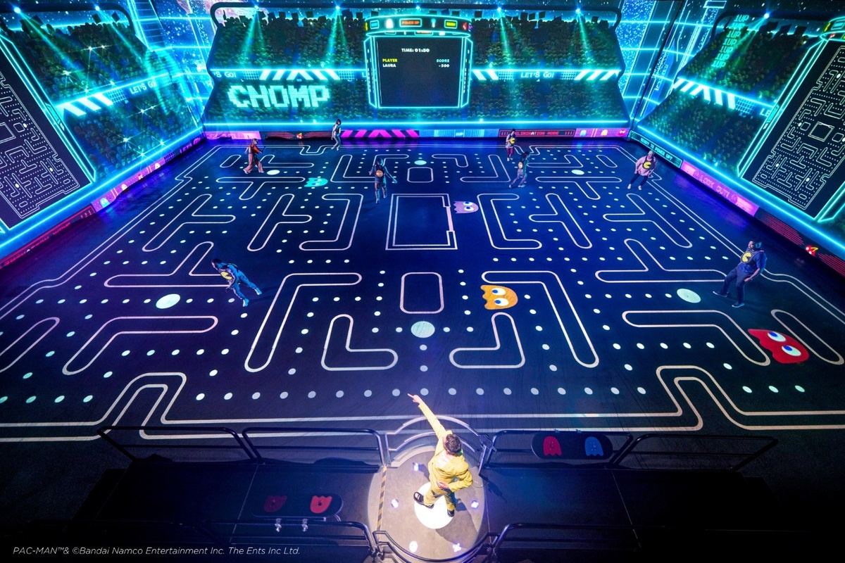 Live-action Pac-Man game with people on a large, illuminated maze, resembling the classic arcade.