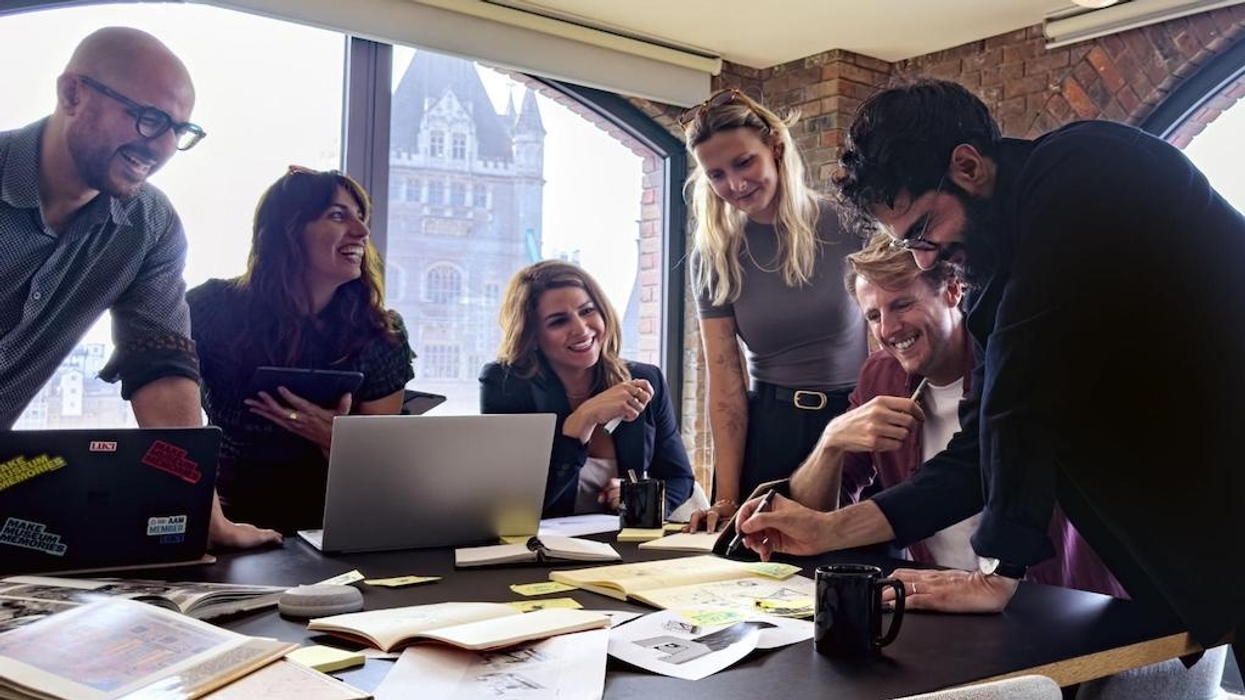Luci team collaborating around a table filled with papers and laptops in a bright office.