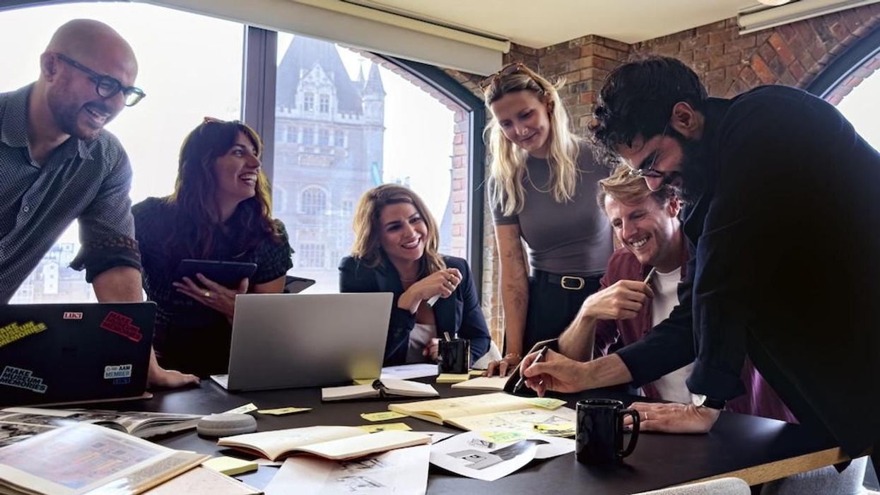 Luci team collaborating around a table filled with papers and laptops in a bright office.
