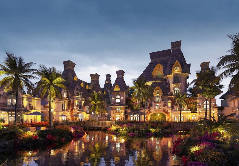 Luxurious, illuminated resort with palm trees and pond at dusk.