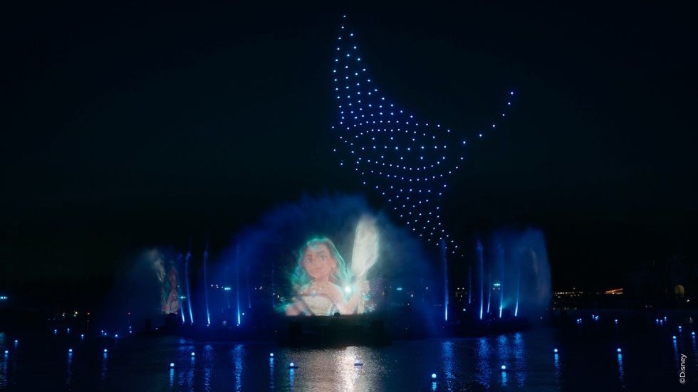 Magical light show with blue drones and character projection on water.