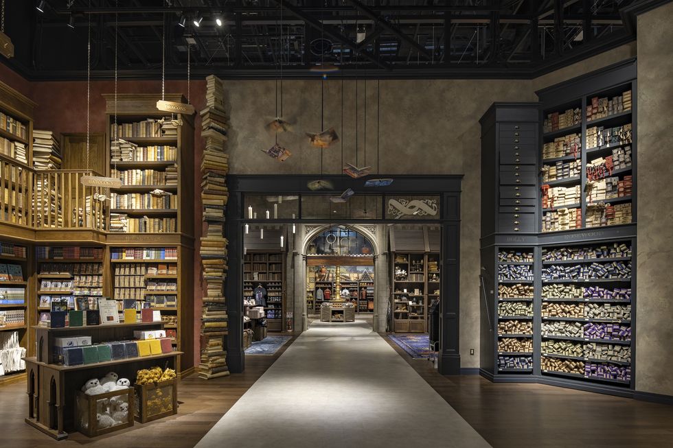 Magical-themed store interior with shelves of books and wands, and floating items above.