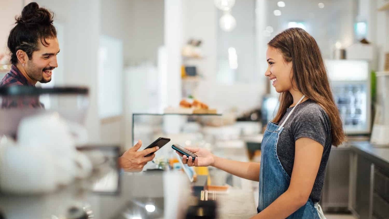 Male customer paying with NFC technology with smartphone at coffee shop. , Man paying for his order in restaurant by mobile phone while bringing it near payment machine in hand hands on female cashier. smeetz