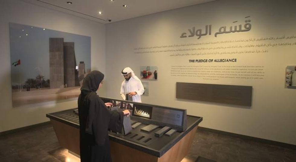 man and woman in Arab clothing interact with Thinkwell Group's new visitor centre experience for Wahat Al Karama Memorial, Abu Dhabi