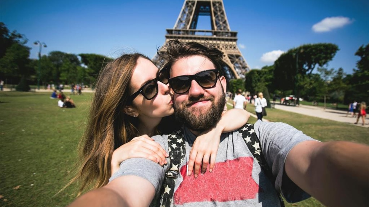 man and woman take selfie at eiffel tower