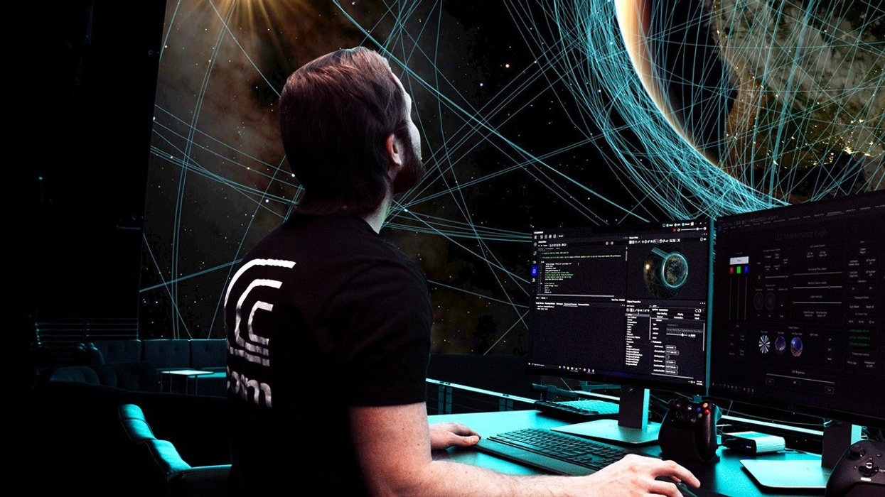 Man at computer with virtual space interface displaying planetary and network visuals.