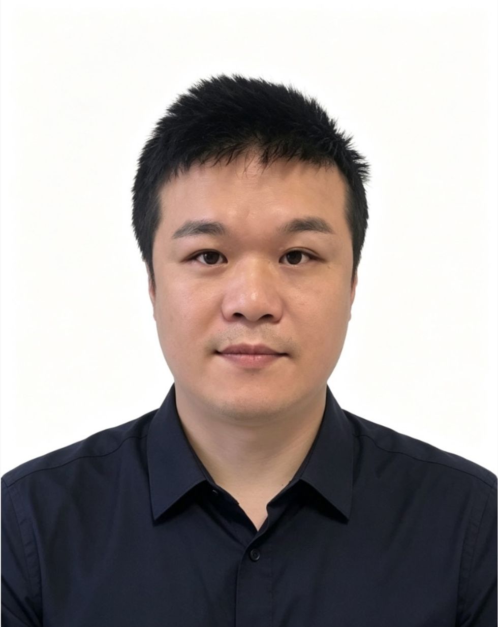 Man in a dark shirt standing against a plain white background.