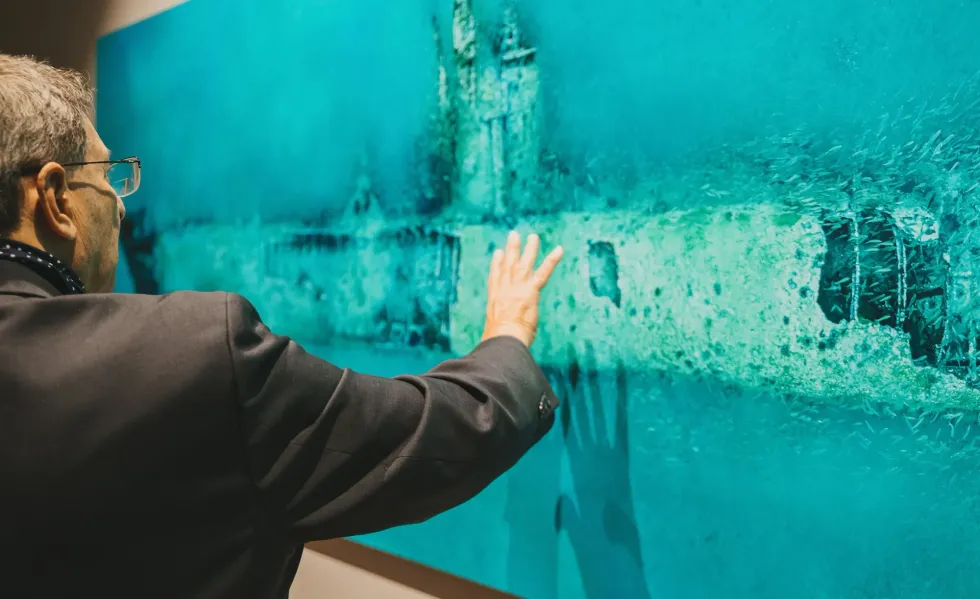 Man in suit looks at underwater photography at Oceans exhibition