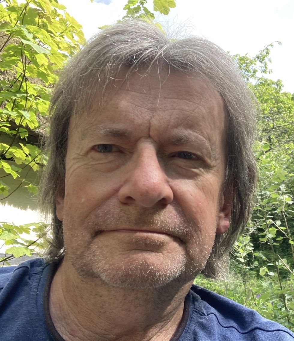 Man named Richard Parry wearing a blue shirt, surrounded by greenery.