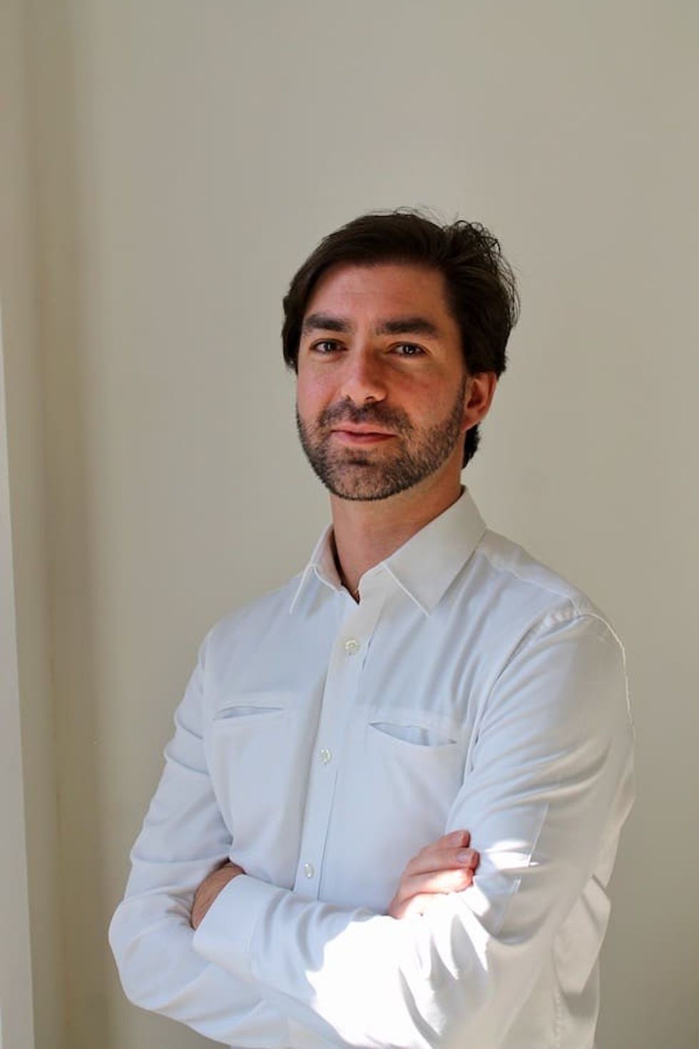 Man named \u200bDr Marti\u0301n Zordan in a white shirt with crossed arms, standing against a beige wall.