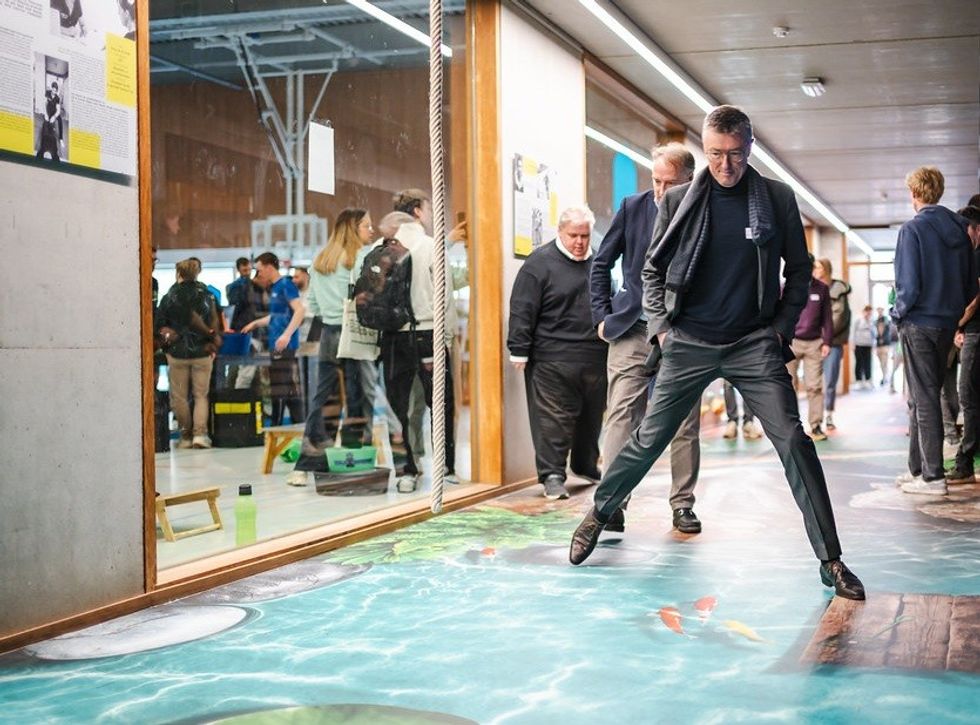 Man playfully balancing on a 3D floor painting of water and stepping stones.