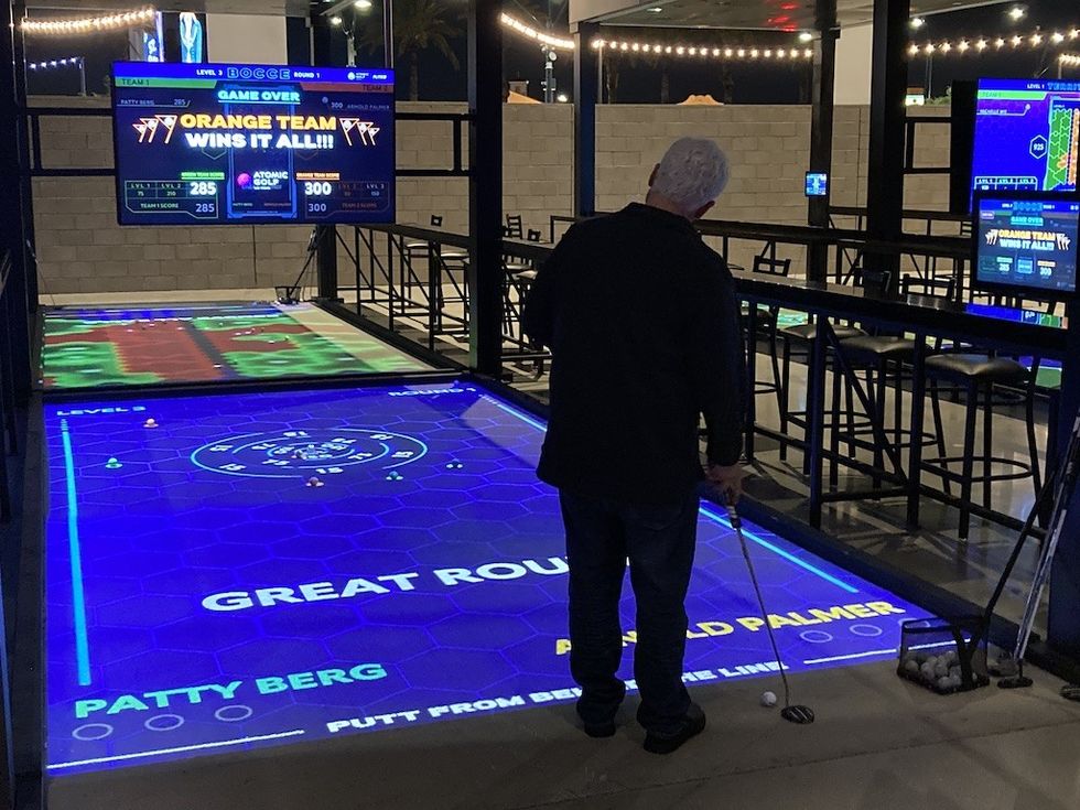 Man playing interactive mini-golf game at Putting District, powered by Beaudry Interactive tech