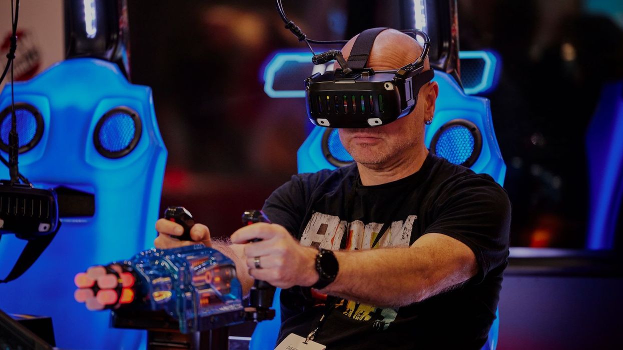 Man plays a VR game wearing a headset, seated at a gaming setup with blue lights.