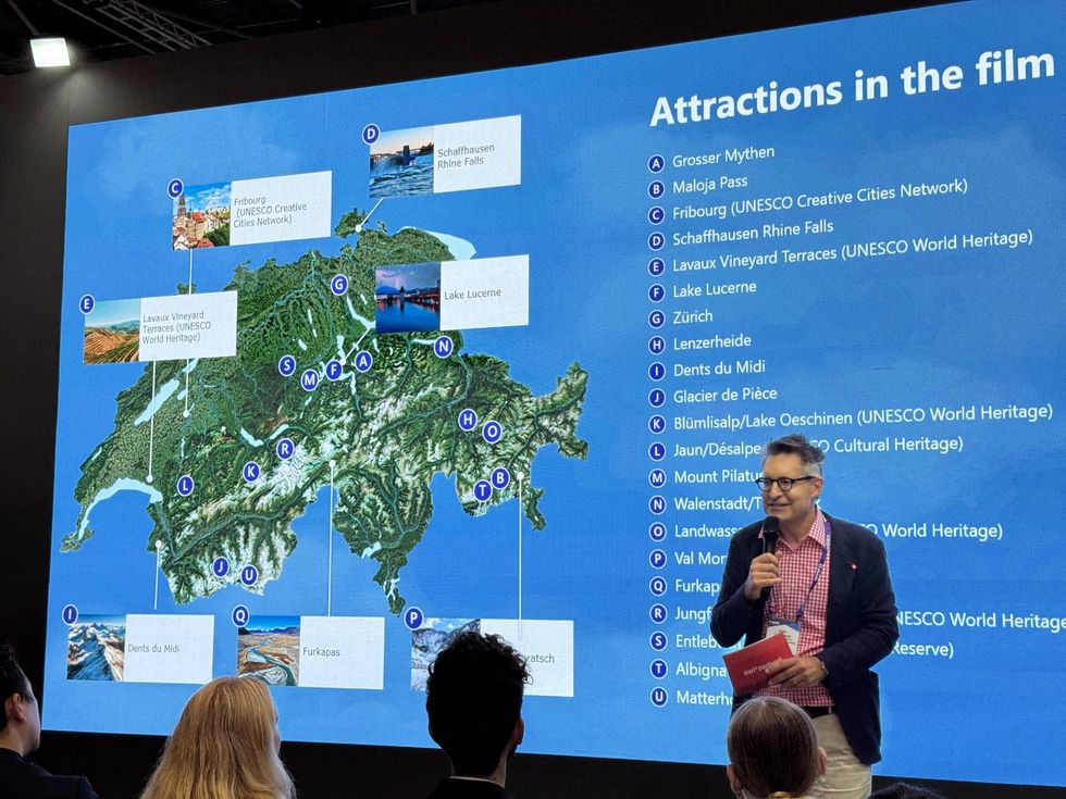 Man presenting a map of Swiss attractions on a large screen.