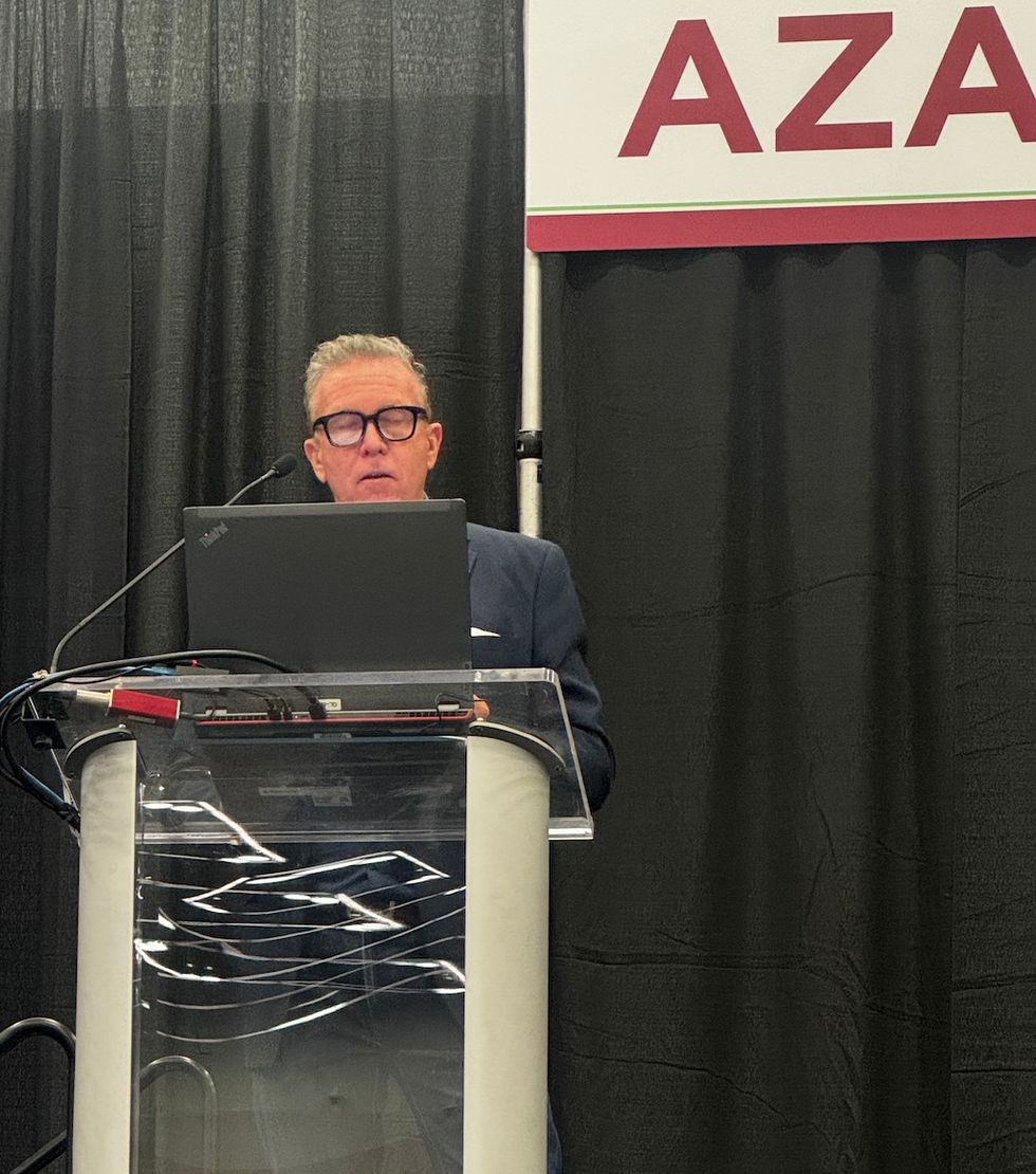 Man presenting at a podium with a laptop and microphone.