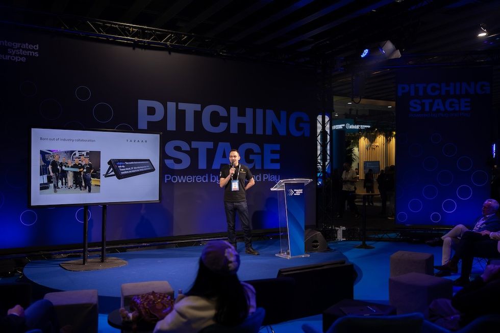 Man presenting on stage with slideshow at tech conference.