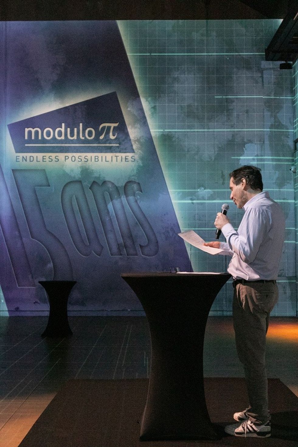 Man speaking on stage at Modulo Pi's 15th anniversary event.