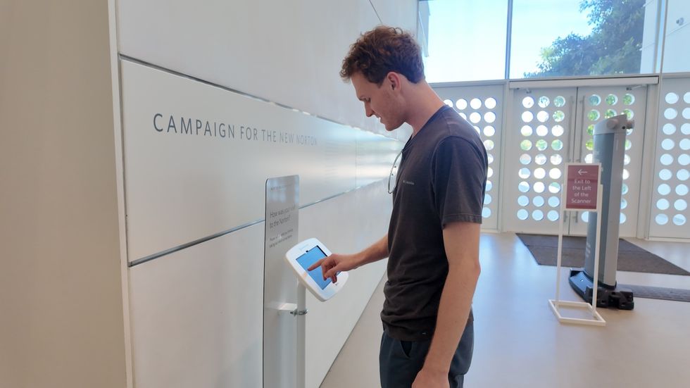 Man using a touchscreen kiosk in a modern lobby.