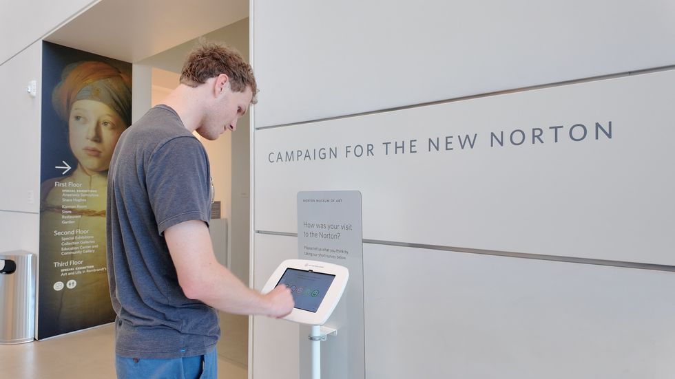 Man using feedback tablet at Norton Museum entrance.