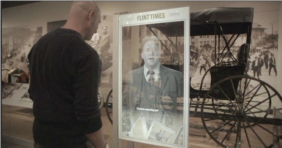 Man viewing an interactive display screen next to a vintage carriage exhibit.