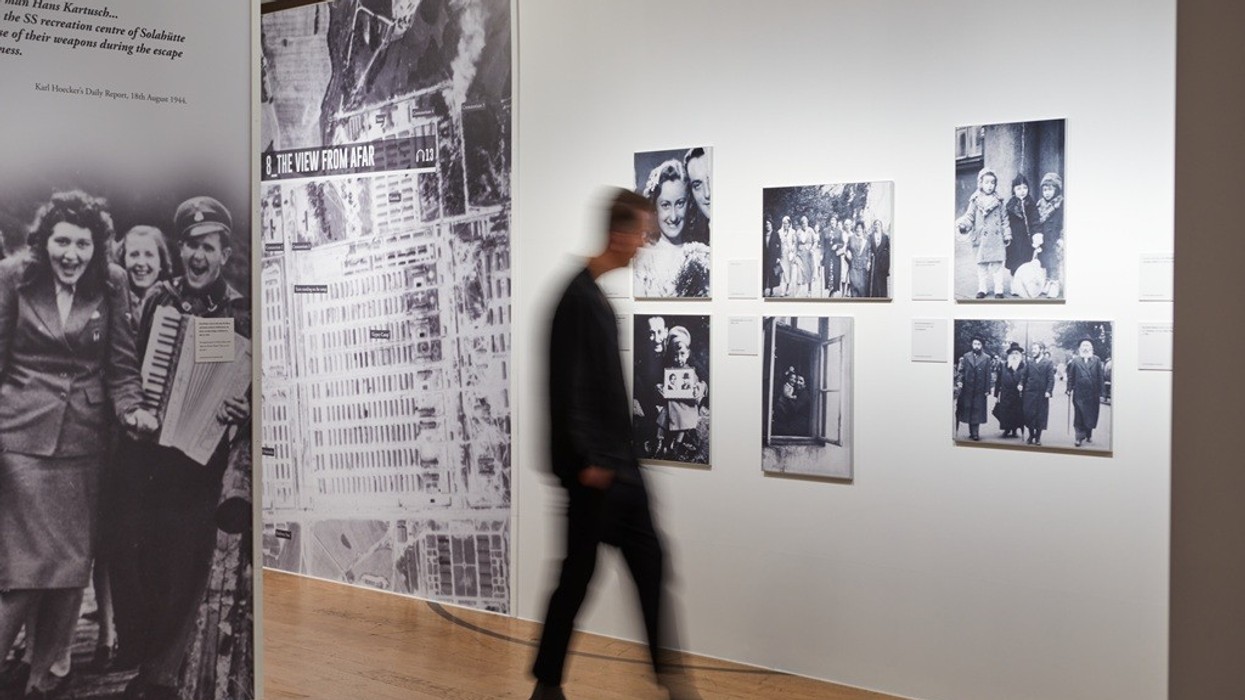 Man walking past a museum exhibit with black-and-white historical photos.