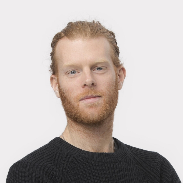 Man with red hair and beard in black sweater, against a plain white background.