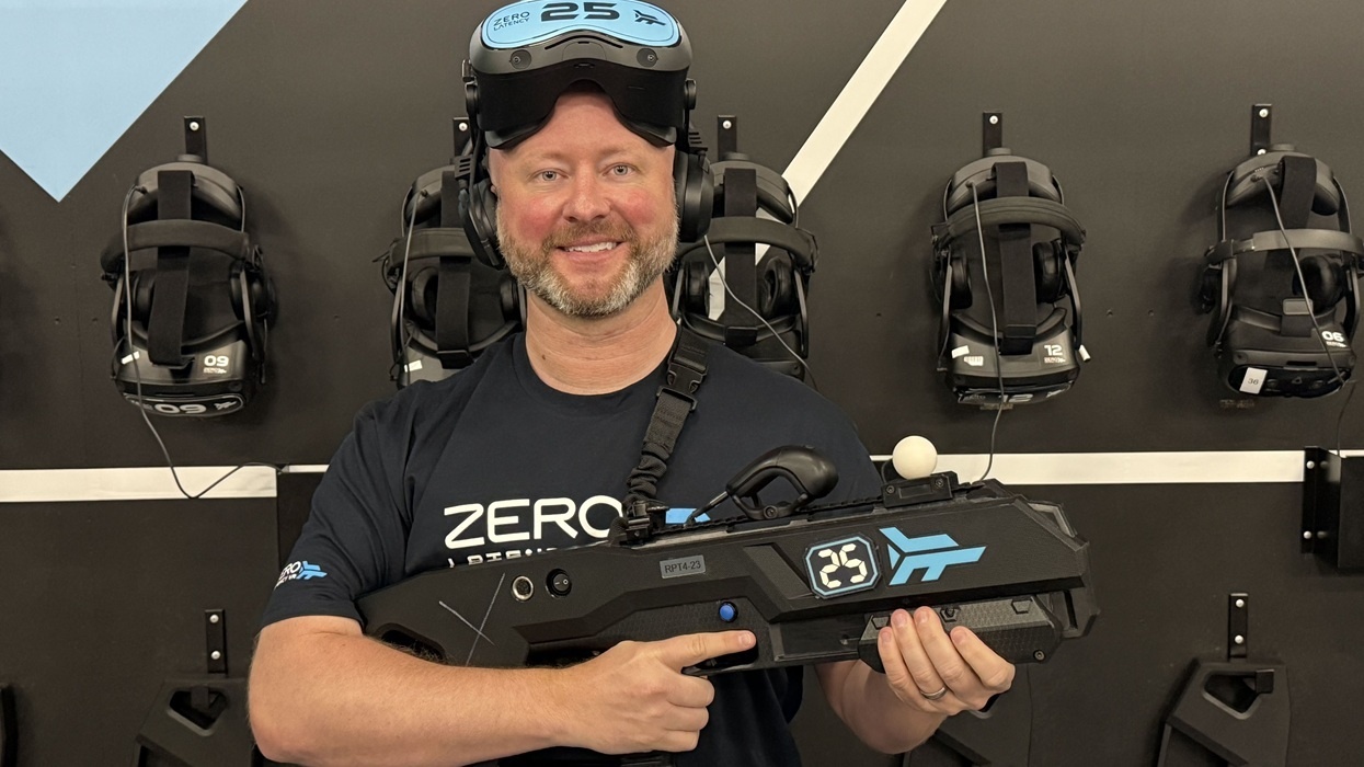 Man with VR headset holding a gaming gun in a tech showroom.