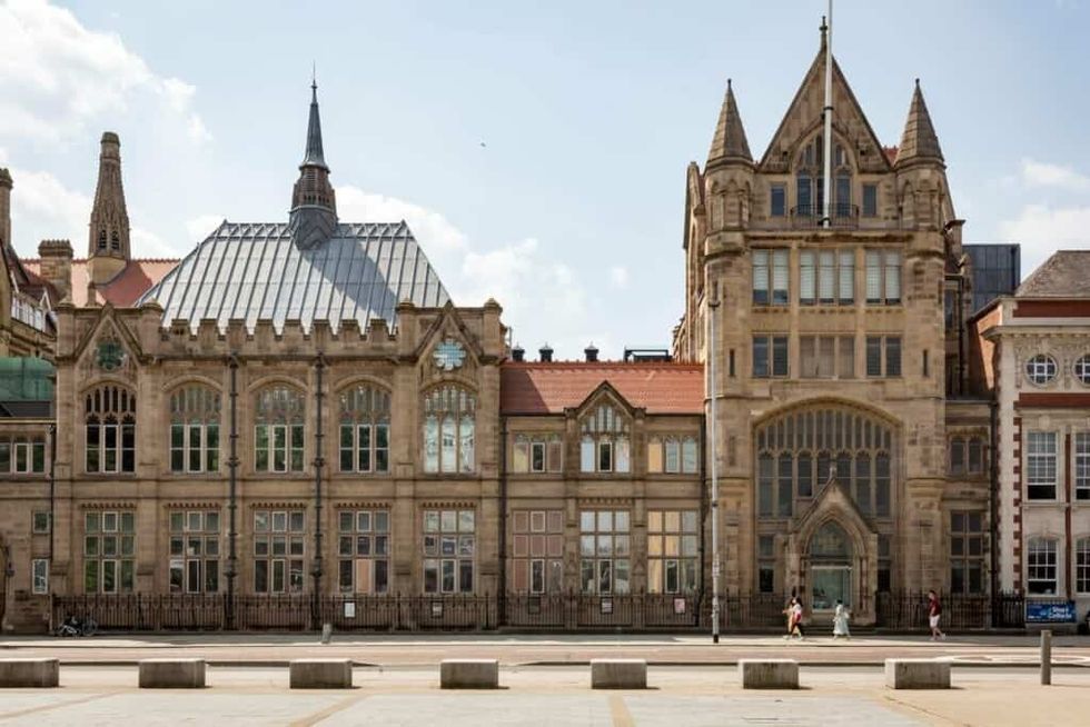 Manchester Museum, an historic stone building with intricate Gothic Revival-style architecture under a blue sky.