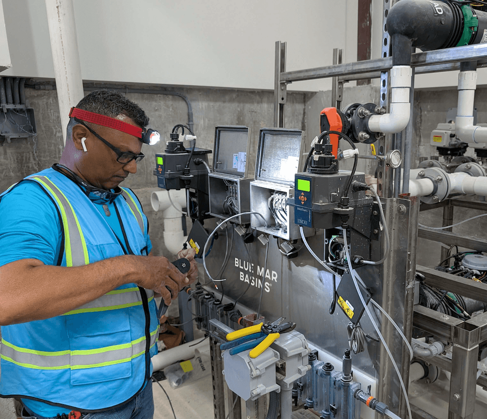 Martin Aquatic technician working on industrial equipment with tools and safety gear.