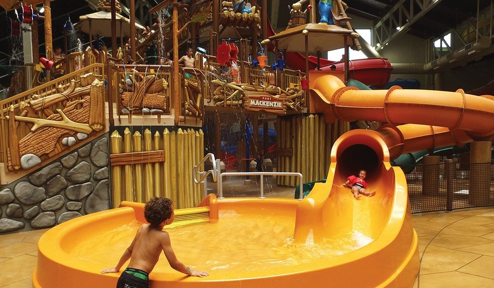 Medium shot of a child about to slide down a kids slide while another child watches
